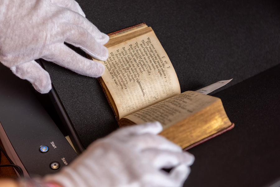person wearing white gloves touching an old book