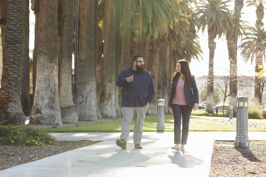 Two professors walking by palm trees