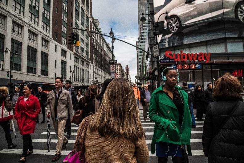 A large number of people using a crosswalk in a busy city