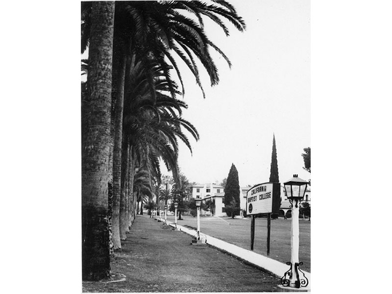 Black and white photograph of Palm Drive and California Baptist College sign, circa 1970s. Queenie Simmons Archive, California Baptist University.