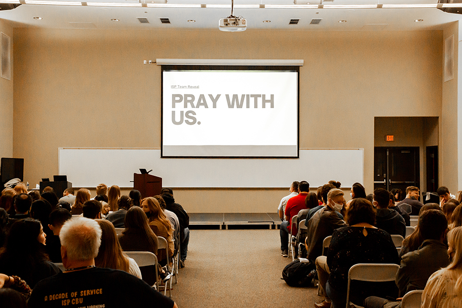 People seated in a classroom looking at a projector 