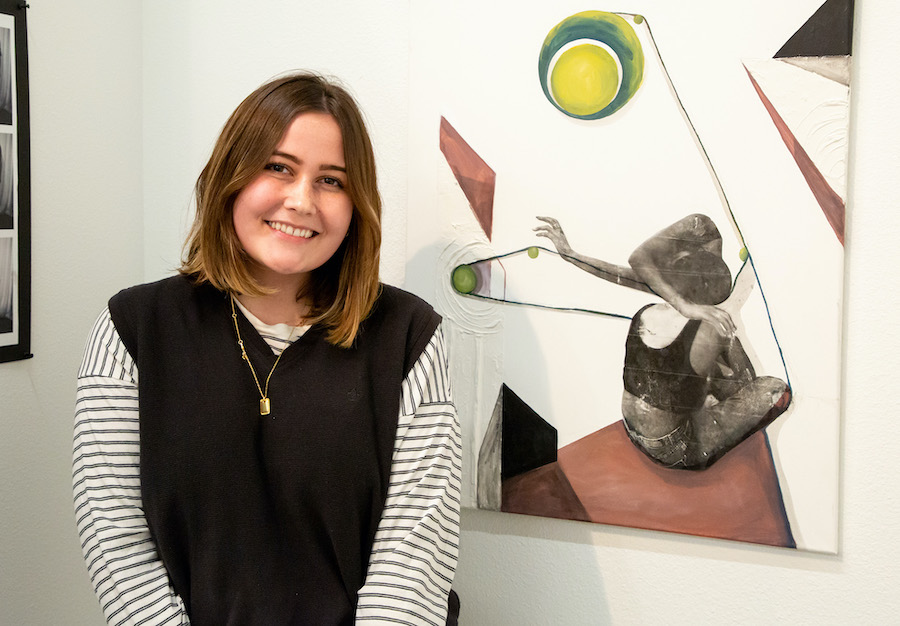 student posing near her artwork