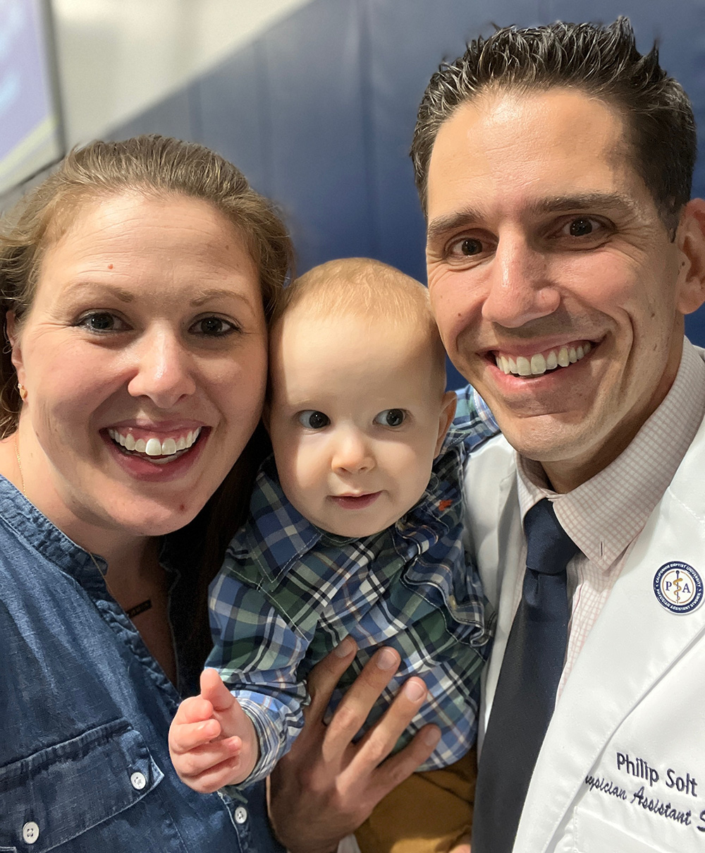 two adults posing with a baby