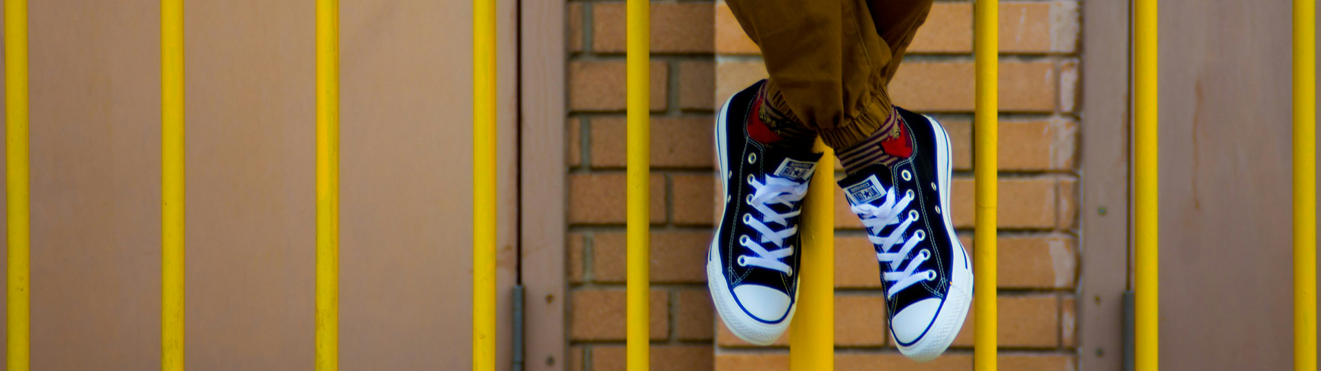 student sitting on yellow fence